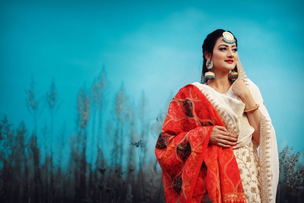 Portrait of a woman in traditional clothing with vibrant colors against a blue sky, showcasing elegance and cultural fashion.