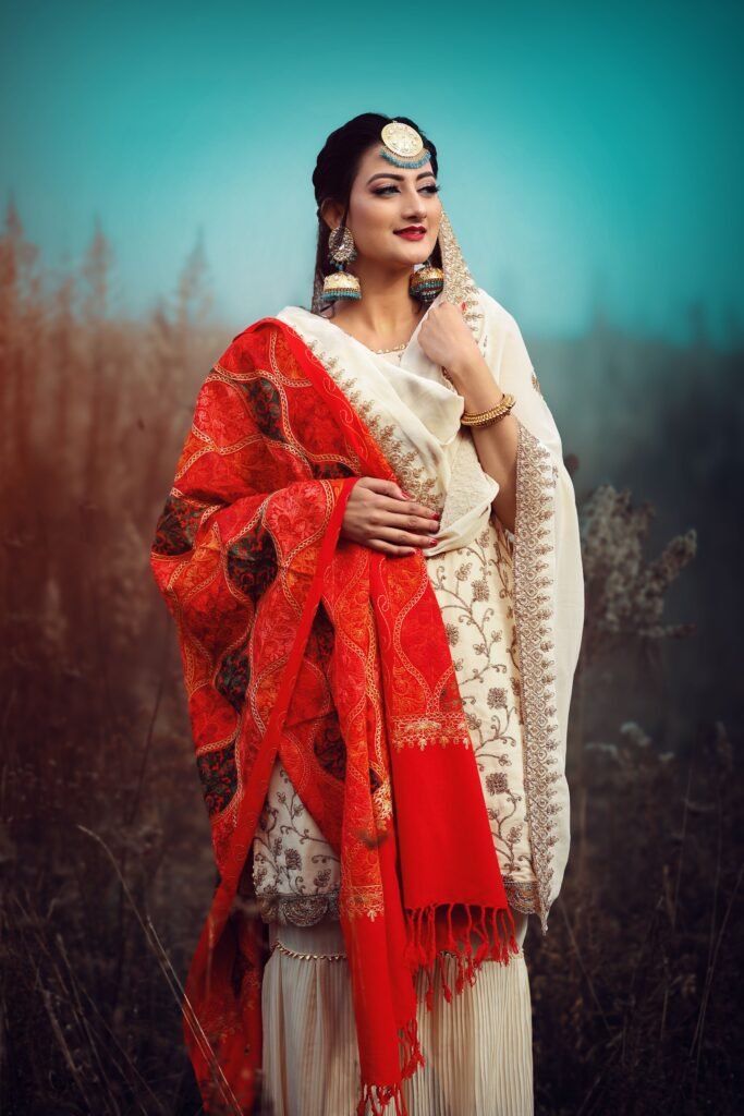 A woman in a vibrant saree poses elegantly amidst a serene outdoor setting.