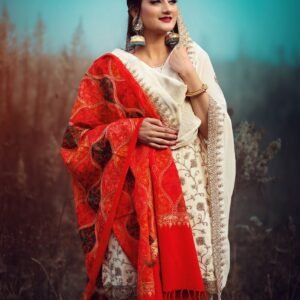 A woman in a vibrant saree poses elegantly amidst a serene outdoor setting.